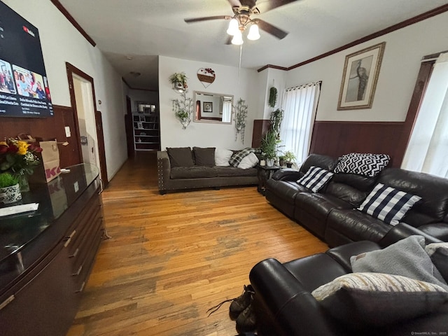 living room featuring hardwood / wood-style floors, wooden walls, ceiling fan, and ornamental molding