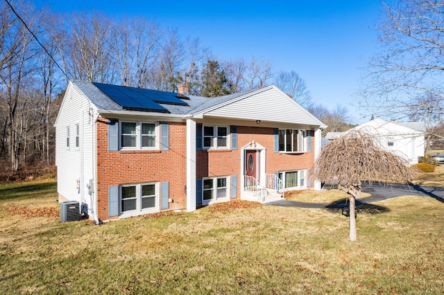 bi-level home featuring solar panels and a front lawn