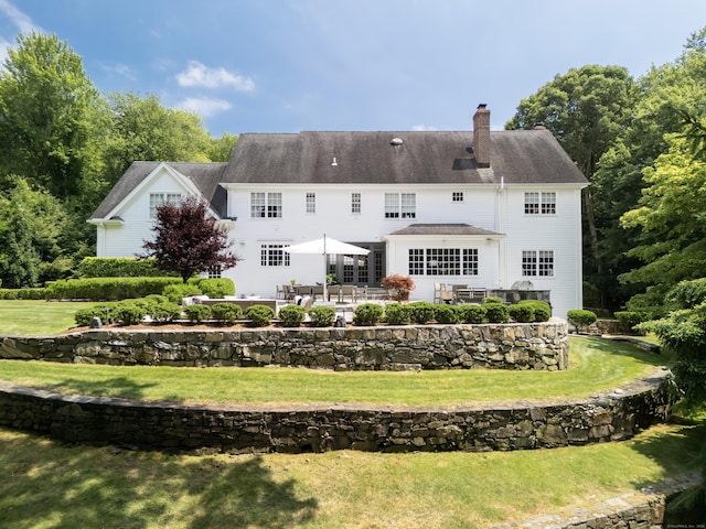 rear view of property featuring a patio and a lawn