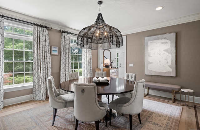 dining room with light hardwood / wood-style flooring, a notable chandelier, and crown molding