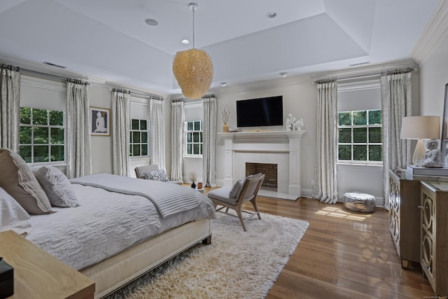 bedroom with a tray ceiling, dark hardwood / wood-style floors, and ornamental molding