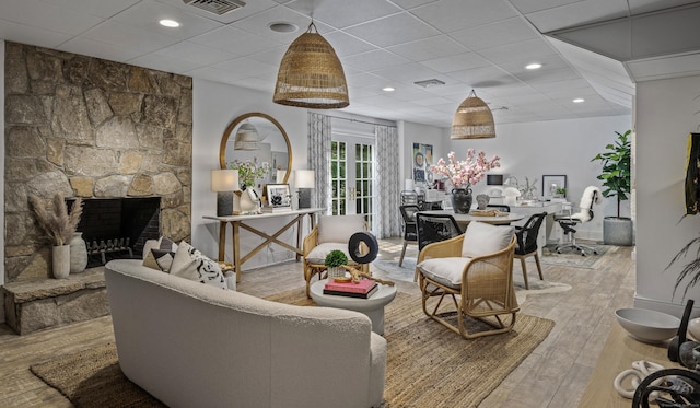 living room featuring a fireplace, light hardwood / wood-style flooring, and a drop ceiling