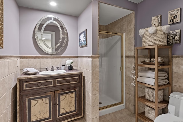 bathroom featuring walk in shower, tile patterned floors, toilet, vanity, and tile walls