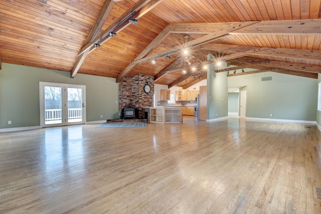 unfurnished living room with beam ceiling, wood ceiling, a wood stove, and light hardwood / wood-style flooring