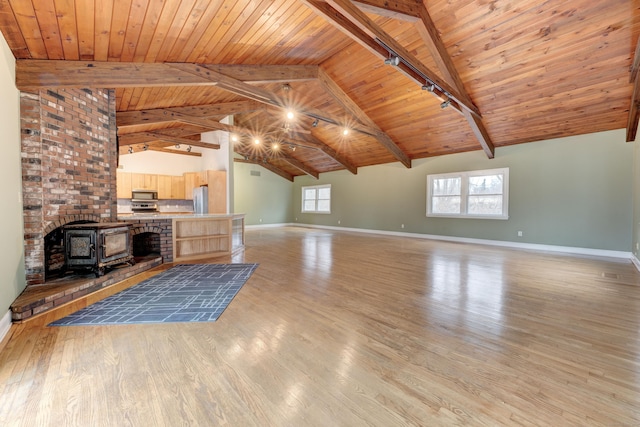 unfurnished living room featuring beam ceiling, a wood stove, wooden ceiling, and light hardwood / wood-style floors