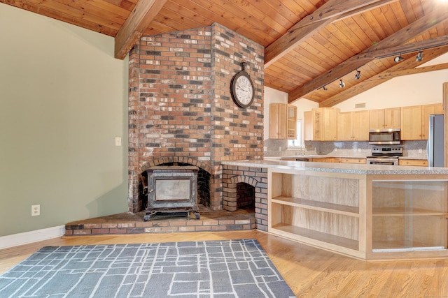 kitchen featuring appliances with stainless steel finishes, light brown cabinetry, tasteful backsplash, vaulted ceiling with beams, and a wood stove