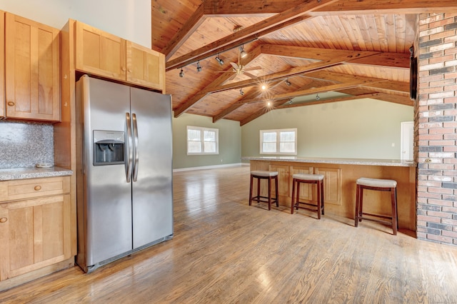 kitchen featuring light brown cabinets, wooden ceiling, a kitchen breakfast bar, stainless steel fridge, and tasteful backsplash