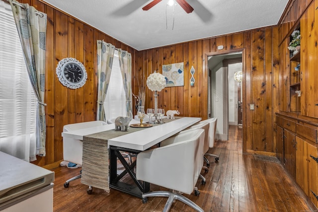 office area featuring ceiling fan, dark hardwood / wood-style flooring, a textured ceiling, and wooden walls