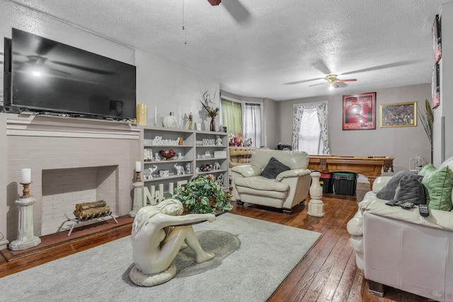 living room featuring dark hardwood / wood-style floors, a fireplace, a textured ceiling, and pool table