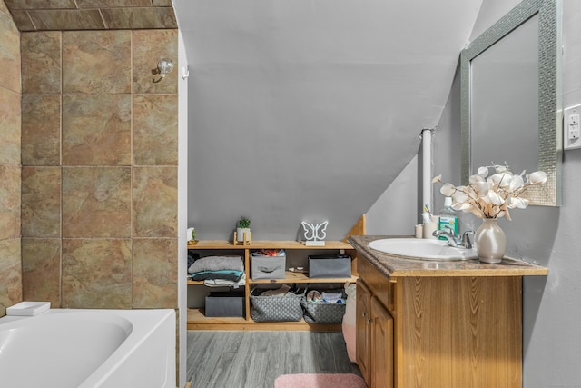 bathroom featuring hardwood / wood-style flooring, vanity, a washtub, and vaulted ceiling