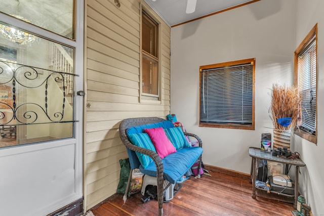 sitting room with hardwood / wood-style flooring, wood walls, and ornamental molding