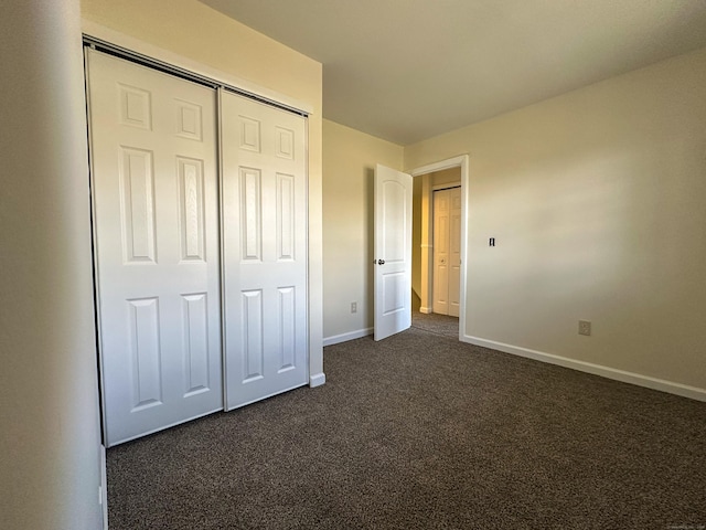 unfurnished bedroom with dark colored carpet and a closet