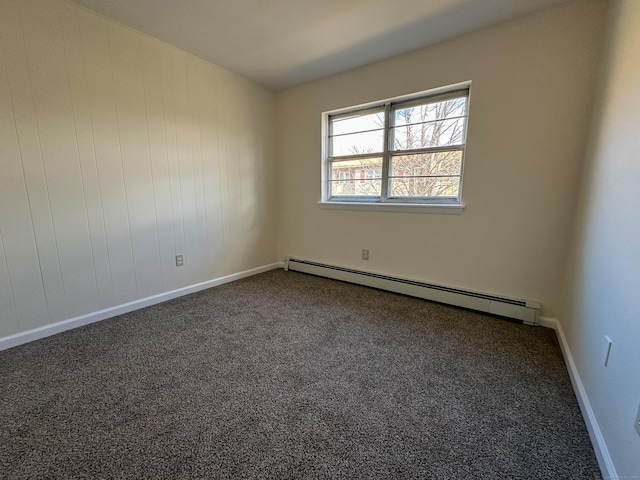 carpeted spare room featuring a baseboard radiator and wood walls