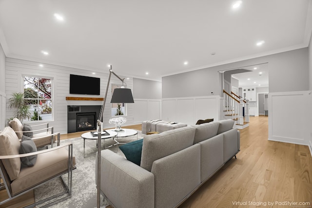 living room with ornamental molding, light wood-type flooring, a fireplace, and recessed lighting