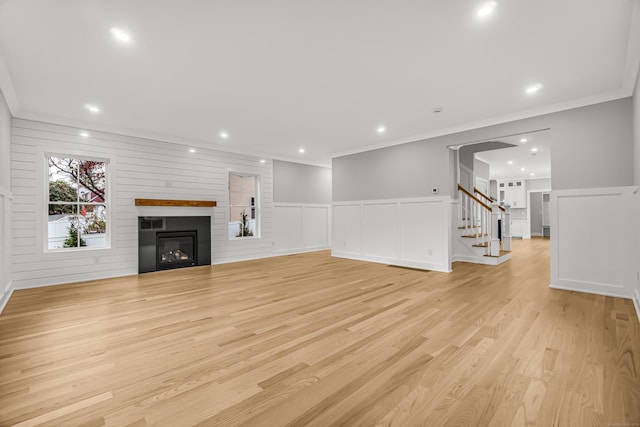 unfurnished living room with a large fireplace, stairs, crown molding, light wood-style floors, and recessed lighting