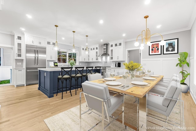 dining room featuring recessed lighting, a wainscoted wall, a decorative wall, light wood-type flooring, and crown molding