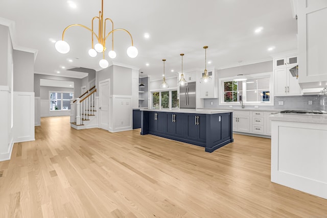 kitchen featuring built in refrigerator, ornamental molding, white cabinets, and light countertops