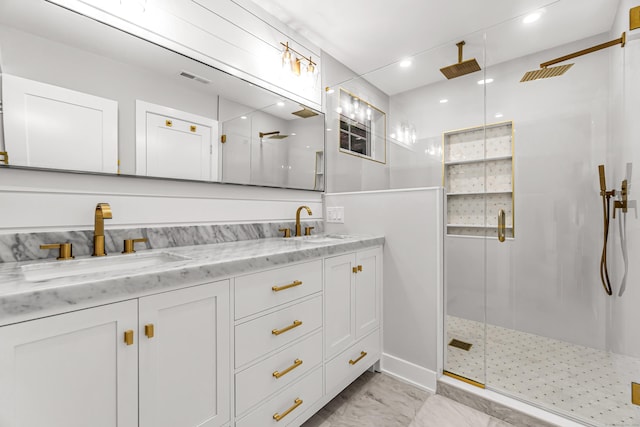 full bath with visible vents, a sink, a shower stall, and double vanity