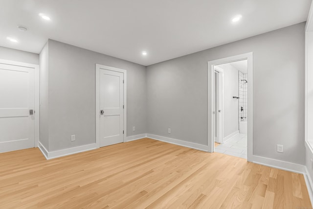 empty room featuring light wood finished floors, recessed lighting, and baseboards