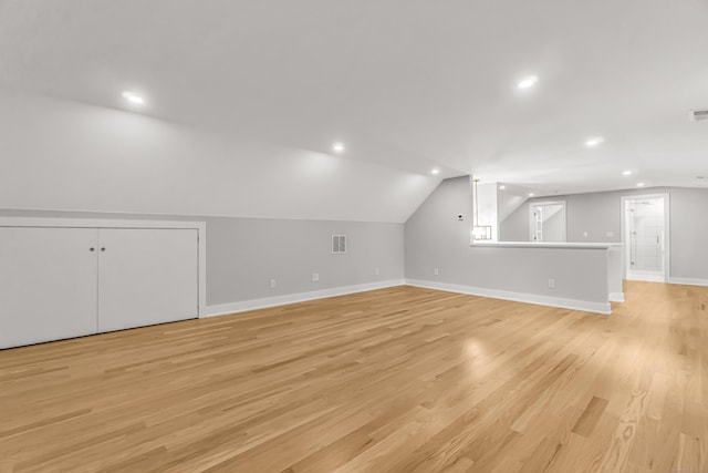 additional living space featuring baseboards, visible vents, vaulted ceiling, and light wood finished floors