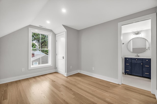 additional living space with lofted ceiling, a sink, visible vents, baseboards, and light wood-type flooring