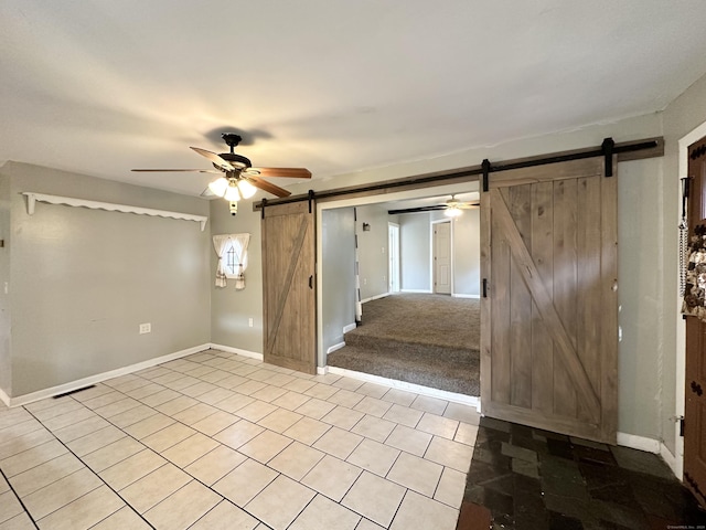 empty room with light carpet, a barn door, and ceiling fan