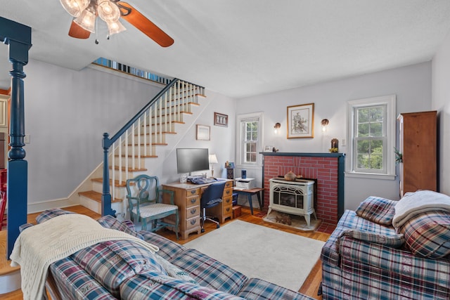 living room with ceiling fan, a wood stove, and light hardwood / wood-style flooring