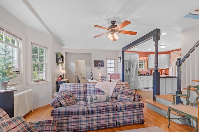 living room featuring ceiling fan, a healthy amount of sunlight, radiator, and light hardwood / wood-style flooring