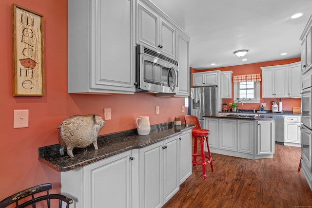 kitchen with appliances with stainless steel finishes, dark hardwood / wood-style flooring, and white cabinetry