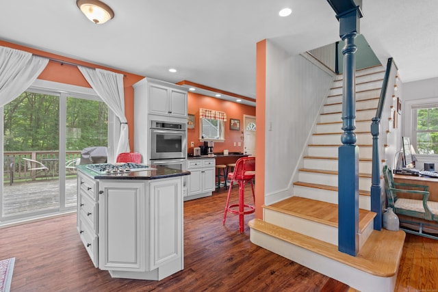 kitchen featuring white cabinetry, a kitchen island, stainless steel appliances, and dark hardwood / wood-style floors