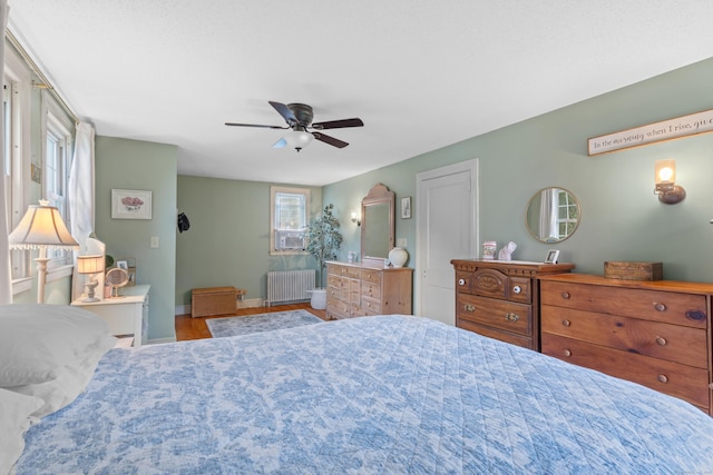 bedroom featuring hardwood / wood-style flooring, radiator, and ceiling fan