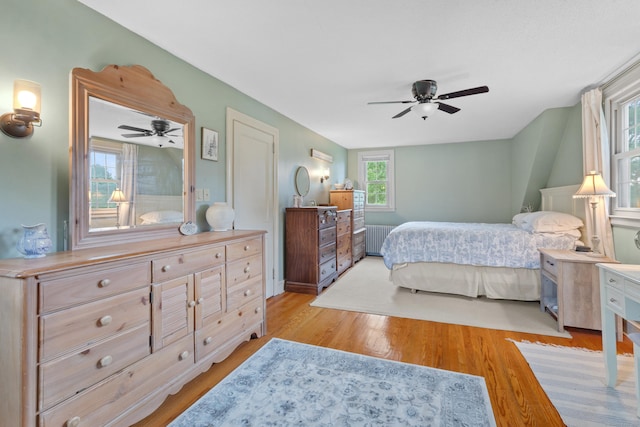 bedroom featuring radiator heating unit, light hardwood / wood-style flooring, and ceiling fan