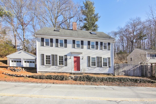 colonial inspired home featuring a garage and an outbuilding