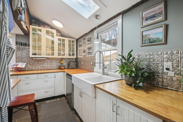 kitchen with butcher block countertops, hanging light fixtures, vaulted ceiling with skylight, and white cabinets