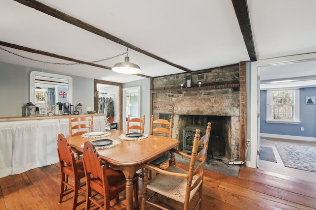 dining room featuring hardwood / wood-style flooring, a large fireplace, and beam ceiling