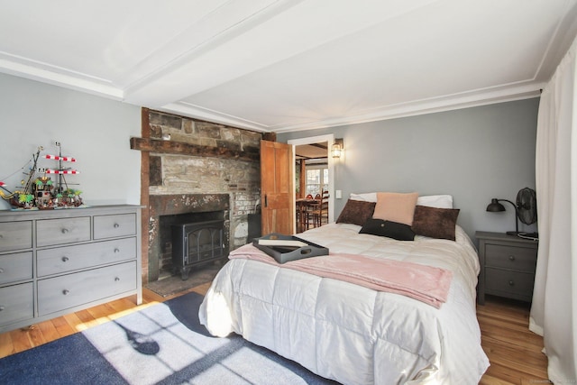 bedroom featuring ornamental molding, light hardwood / wood-style flooring, and a wood stove