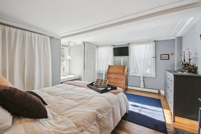 bedroom featuring a baseboard radiator and light hardwood / wood-style floors