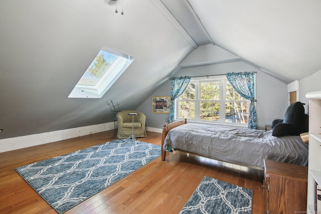 bedroom with hardwood / wood-style flooring and vaulted ceiling with skylight