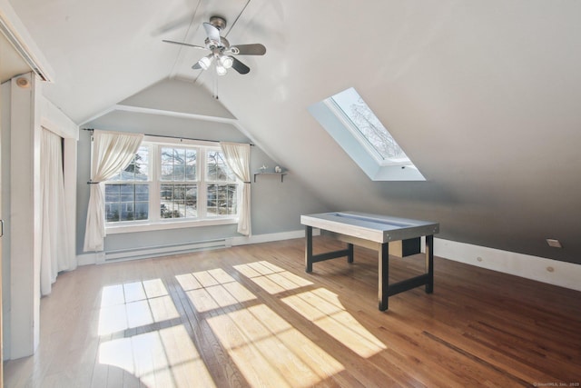 additional living space featuring light hardwood / wood-style flooring, a baseboard radiator, lofted ceiling with skylight, and ceiling fan