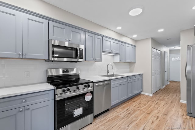 kitchen featuring gray cabinetry, sink, stainless steel appliances, and light hardwood / wood-style floors