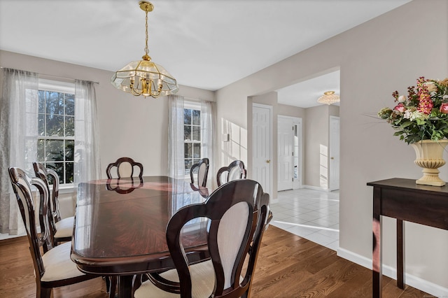 dining area with hardwood / wood-style floors and an inviting chandelier