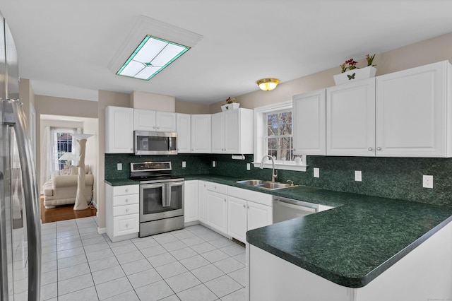 kitchen with white cabinetry, sink, backsplash, kitchen peninsula, and stainless steel appliances