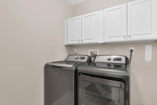 clothes washing area with washing machine and dryer and cabinets