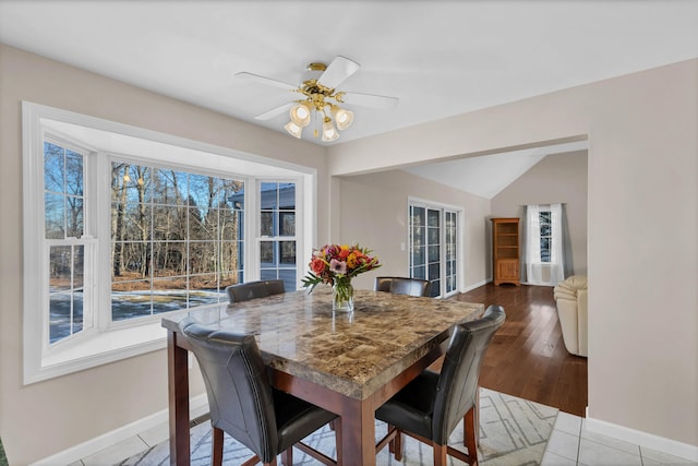 dining room featuring ceiling fan, light hardwood / wood-style floors, vaulted ceiling, and a wealth of natural light