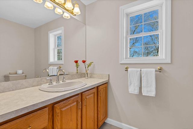 bathroom with an inviting chandelier, vanity, and toilet