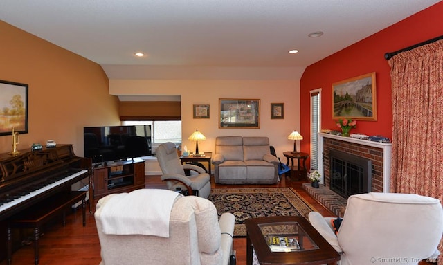 living room featuring lofted ceiling, wood-type flooring, and a brick fireplace