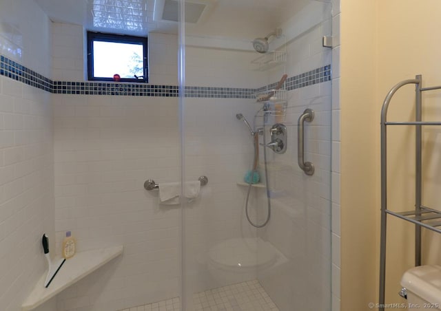 bathroom featuring a shower with door and toilet