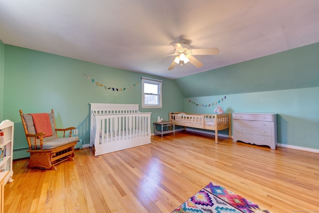 bedroom with light wood-type flooring, vaulted ceiling, ceiling fan, and a baseboard heating unit