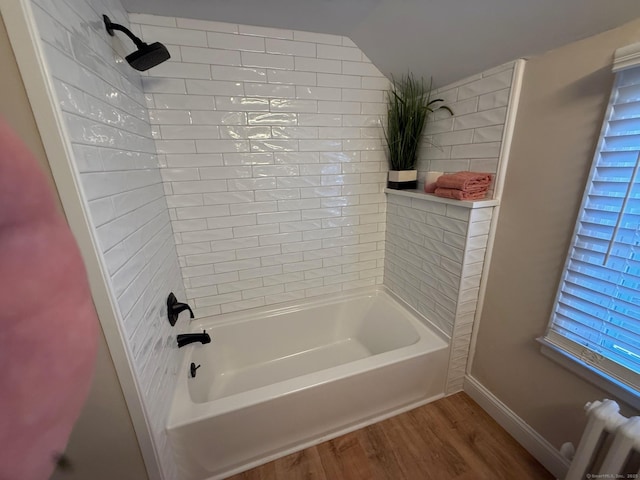 bathroom with radiator heating unit, tiled shower / bath combo, and wood-type flooring