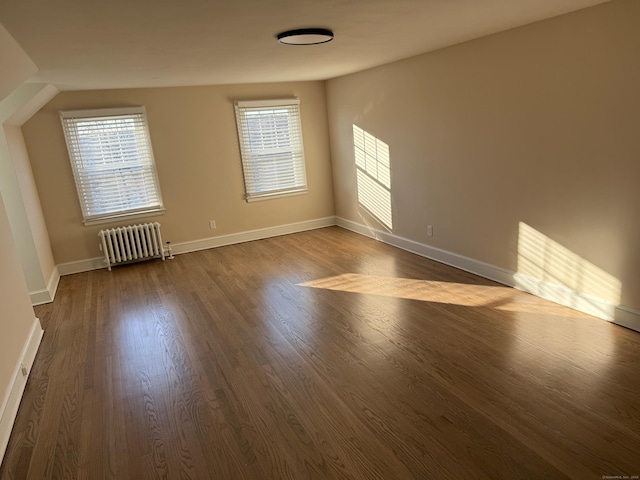 unfurnished room with hardwood / wood-style floors, radiator, and a healthy amount of sunlight